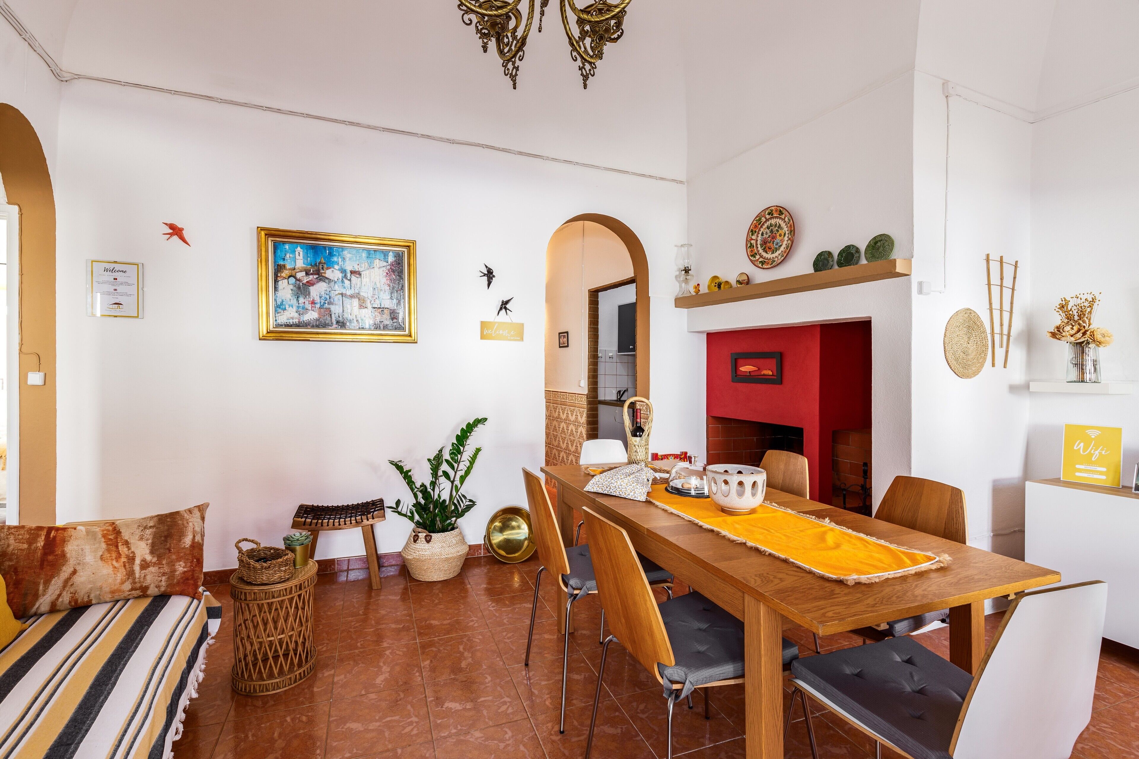 Zona pranzo con tavolo in legno, sedie e parete rossa.