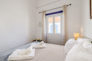 Une chambre d’hôtel avec un lit, une fenêtre avec des rideaux, une lampe de chevet et une serviette sur le sol.