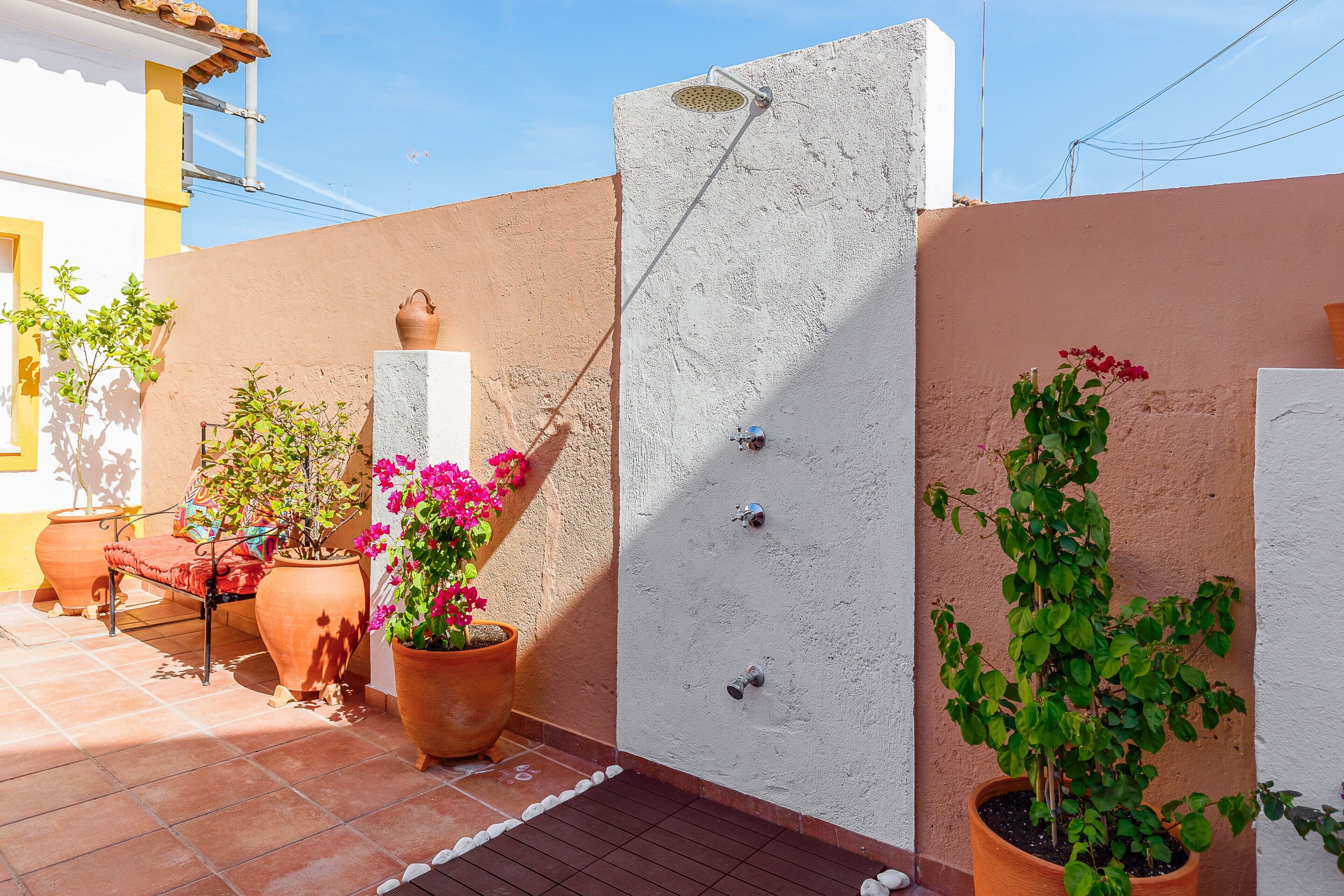 A patio with potted plants, a concrete shower, and a tiled floor.