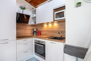 Eine moderne Küche mit weißen Schränken, einer Holzarbeitsplatte, einem eingebauten Backofen, einer Kaffeemaschine und einer Mikrowelle.