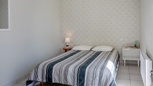 Un dormitorio con cama, mesita de noche, lámpara y radiador.