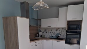 Una cocina moderna con armarios blancos, horno empotrado y cafetera.