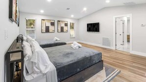 Ein modernes Hotelzimmer mit zwei Betten, einem Flachbildfernseher und Kunstwerken an den Wänden.