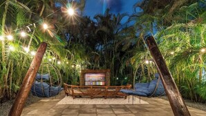 Eine Hängestuhl-Kombination mit einem Fernseher in einem tropischen Garten.