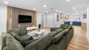 Eine moderne Hotelhalle mit einer Rezeption, einem großen Flachbildfernseher und einer Sitzecke mit grünen Polstersofas.