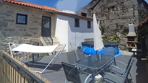 A patio with a table and chairs, a stone building with a red roof, and a wooden fence.