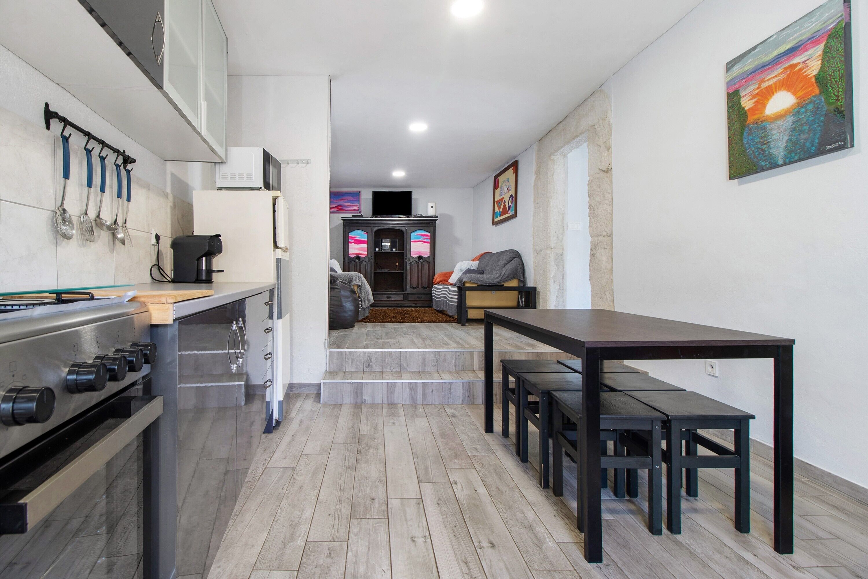 Une cuisine moderne équipée d’une cuisinière à gaz, d’une machine à café et d’un coin repas avec une table et des bancs.