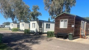 A row of mobile homes with a paved driveway and green bushes. - Gunnedah Tourist Caravan Park (Gunnedah)