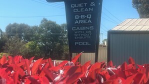A sign for the Gunnedah Tourist Caravan Park, highlighting features such as a quiet and clean area, BBQ facilities, cabins with or without ensuite, and a pool. - Gunnedah Tourist Caravan Park (Gunnedah)