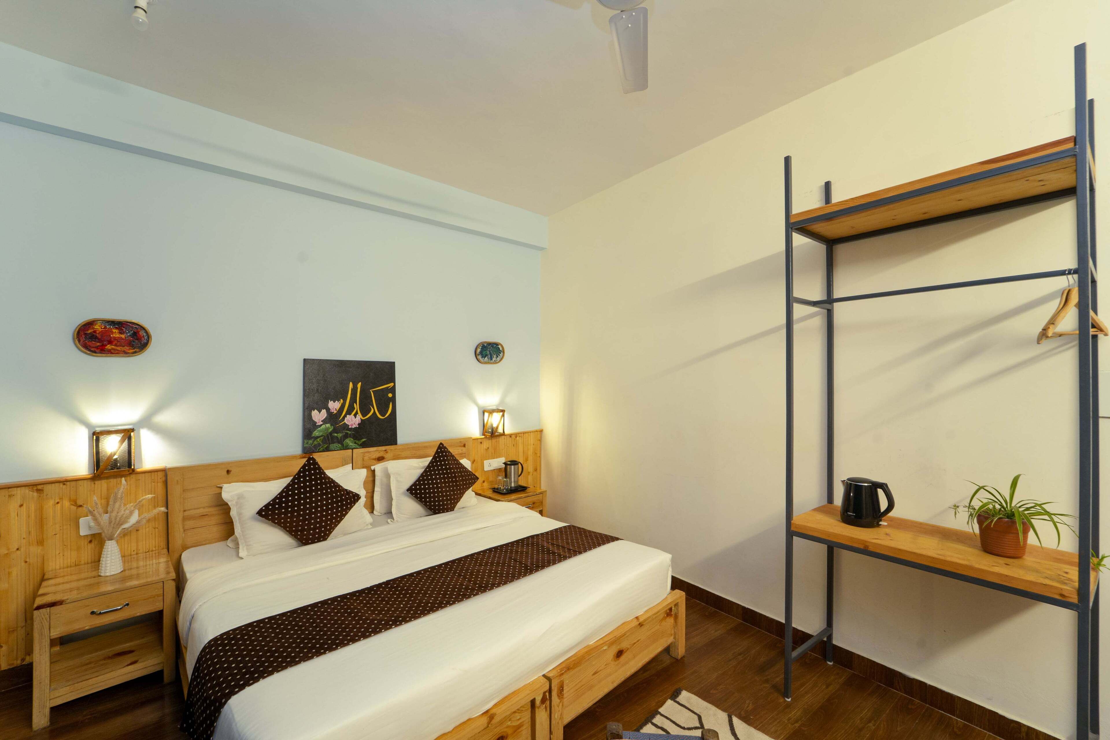 Une chambre à coucher bien rangée, avec un lit en bois, des tables de chevet, une étagère fixée au mur et un ventilateur de plafond.