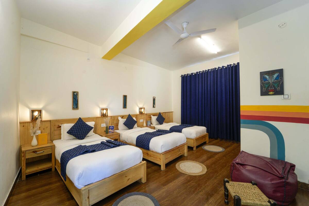 Ein Hotelzimmer mit drei Holzbetten, einem Deckenventilator und Blick nach draußen.