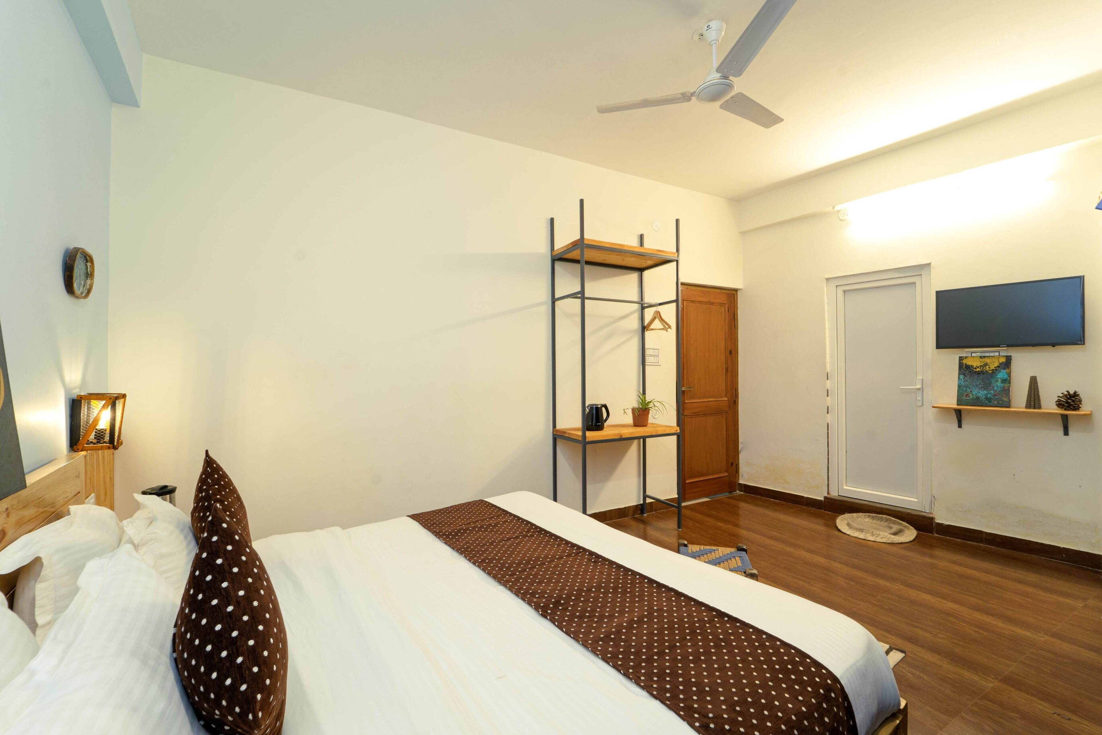 Une chambre à coucher avec un lit, une étagère, un téléviseur et une porte.