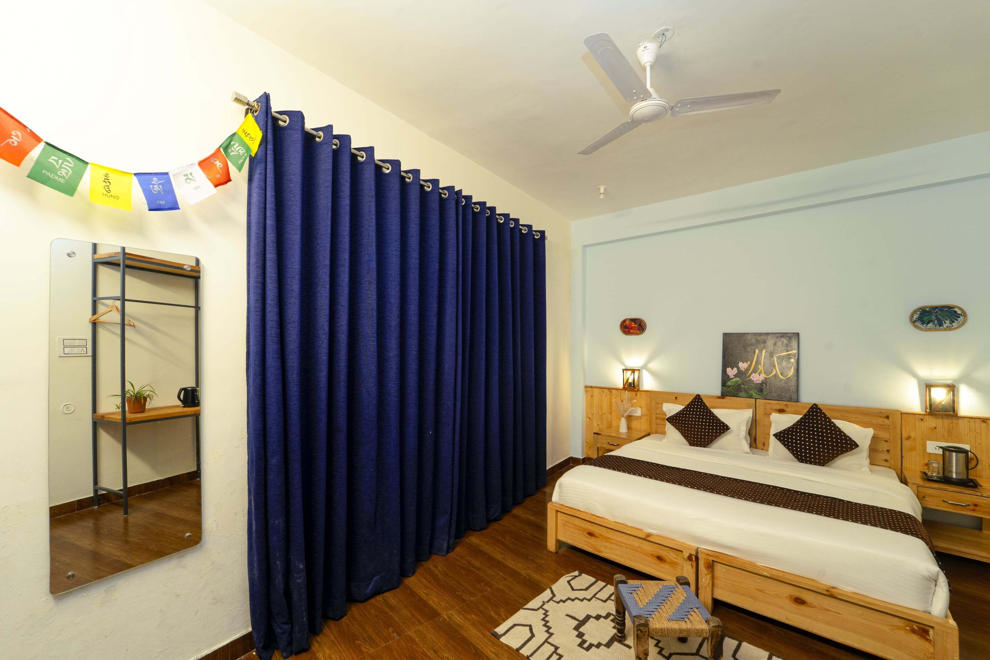 A bedroom with a wooden bed, a ceiling fan, a mirror, and a wall-mounted shelf with a plant.