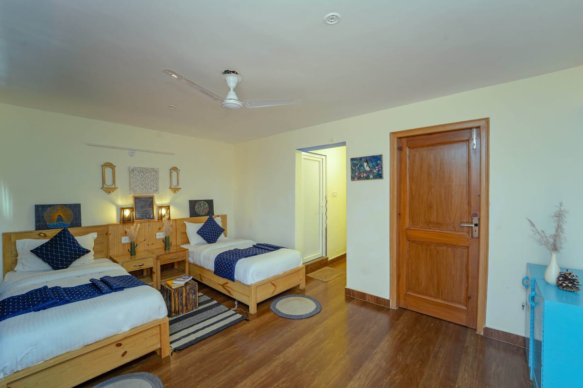 Ein Schlafzimmer mit zwei Betten, Holzmöbeln, einem Deckenventilator und einer Tür.