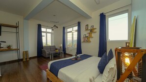 Een slaapkamer met een groot bed, een bureau, een stoel en een raam.