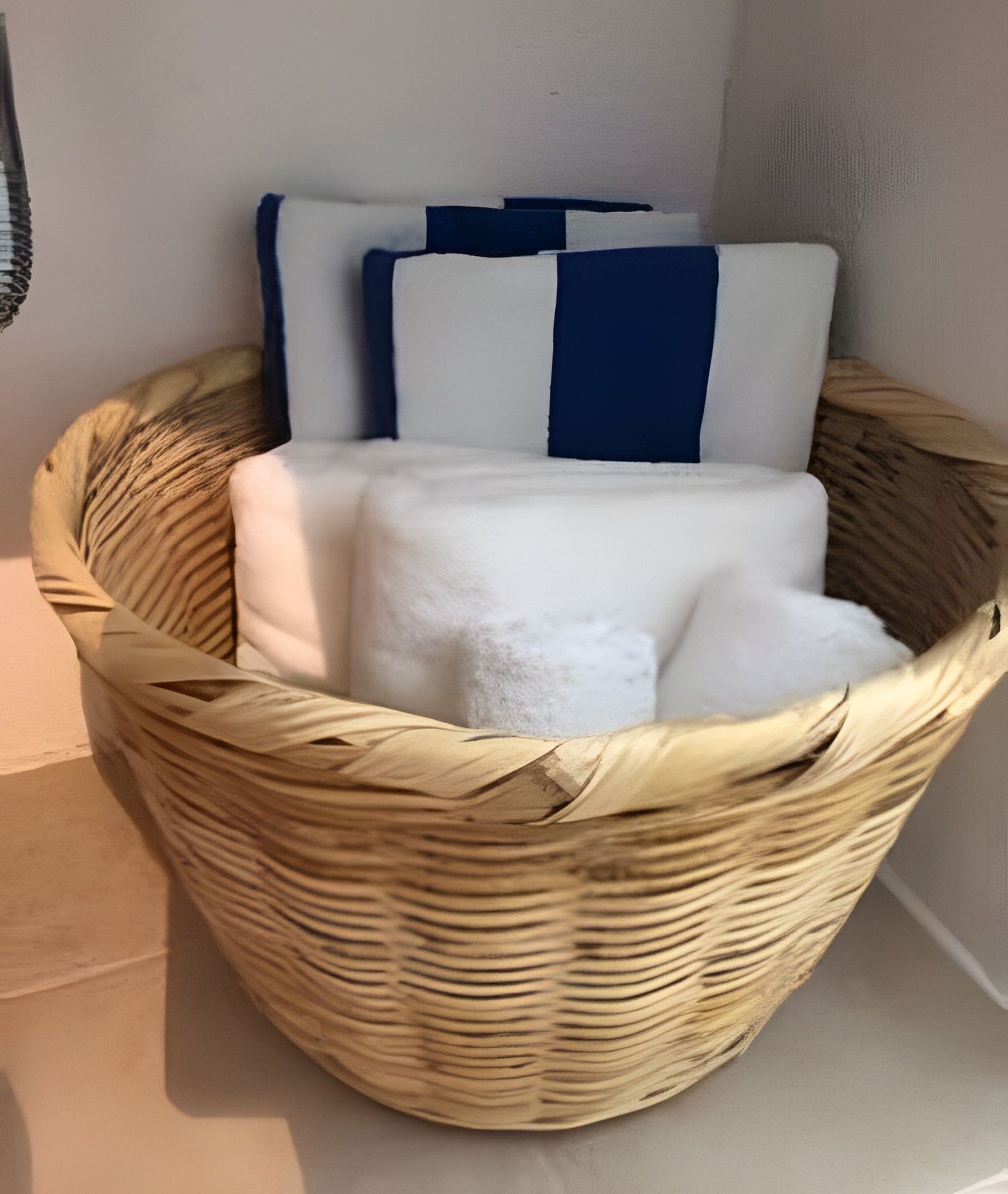 A wicker basket with towels and pillows.