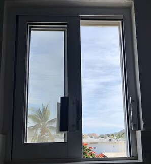 A window with a view of a building and a palm tree.