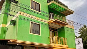 A multi-story building with a green facade, a balcony on the upper floor, and a sign indicating a business establishment. - Princesa El Gallo Inn (Puerto Princesa)