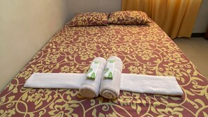 A bed with a floral-patterned bedspread, two rolled towels, and a neatly folded white towel on the bed. - Princesa El Gallo Inn (Puerto Princesa)