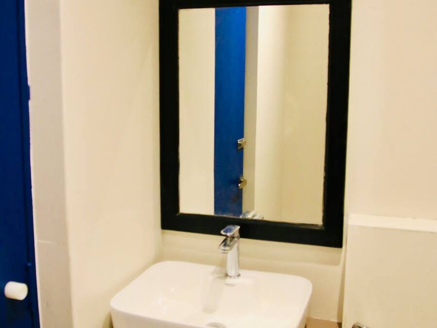A bathroom with a white sink, a mirror with a black frame, and a blue door.