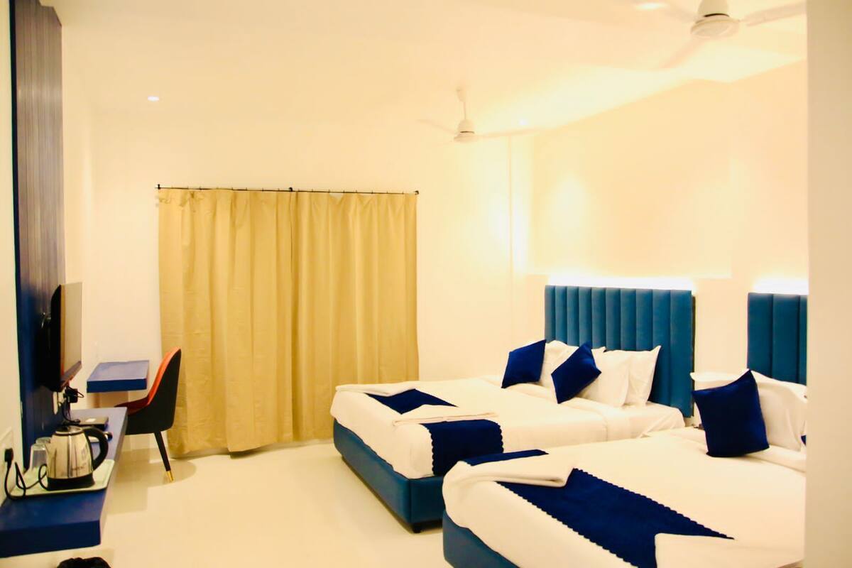 Habitación de hotel con dos camas, un escritorio, una silla y un televisor.