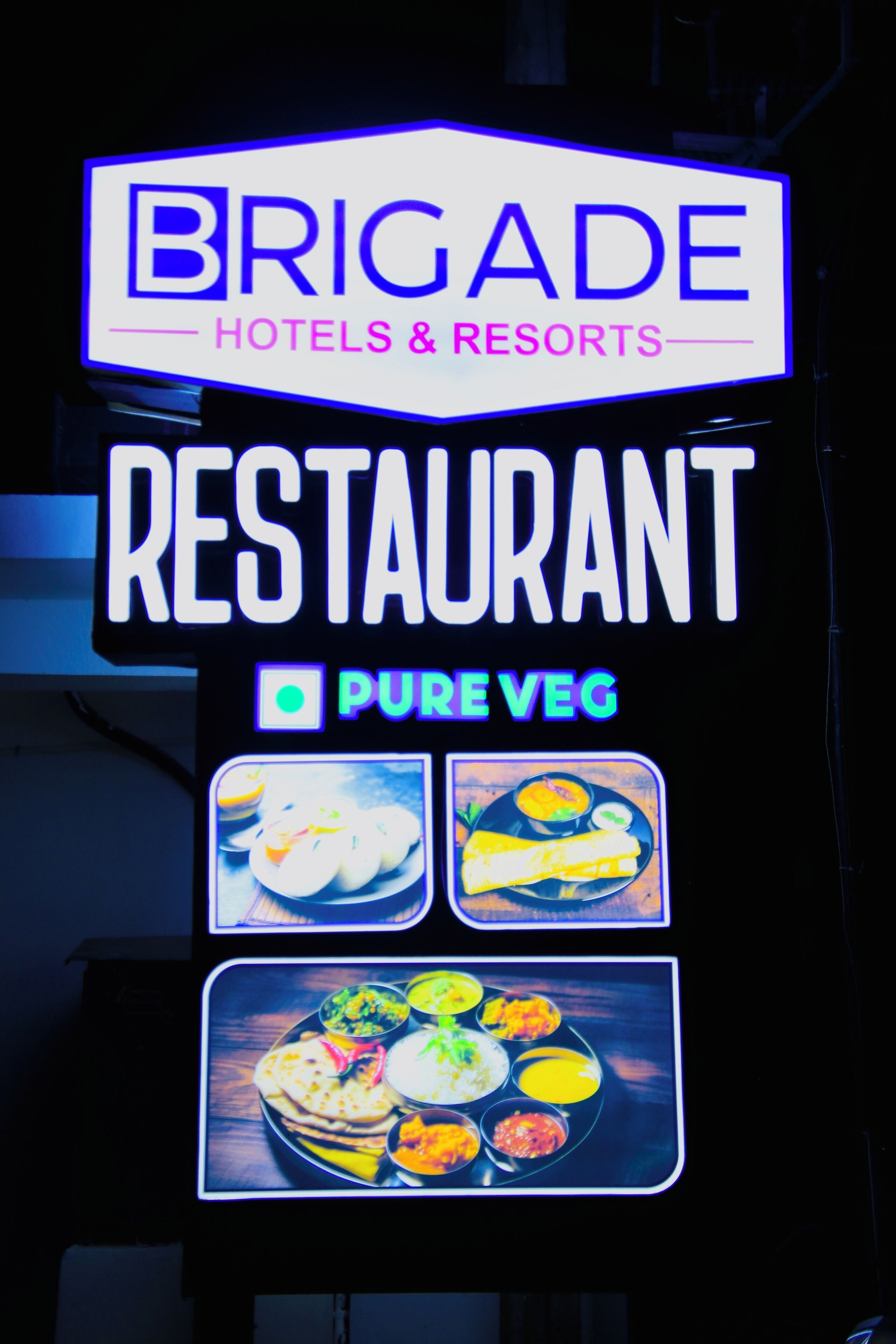 Letreiro de neon do Restaurante Brigade Hotels & Resorts, destacando seu menu vegetariano.