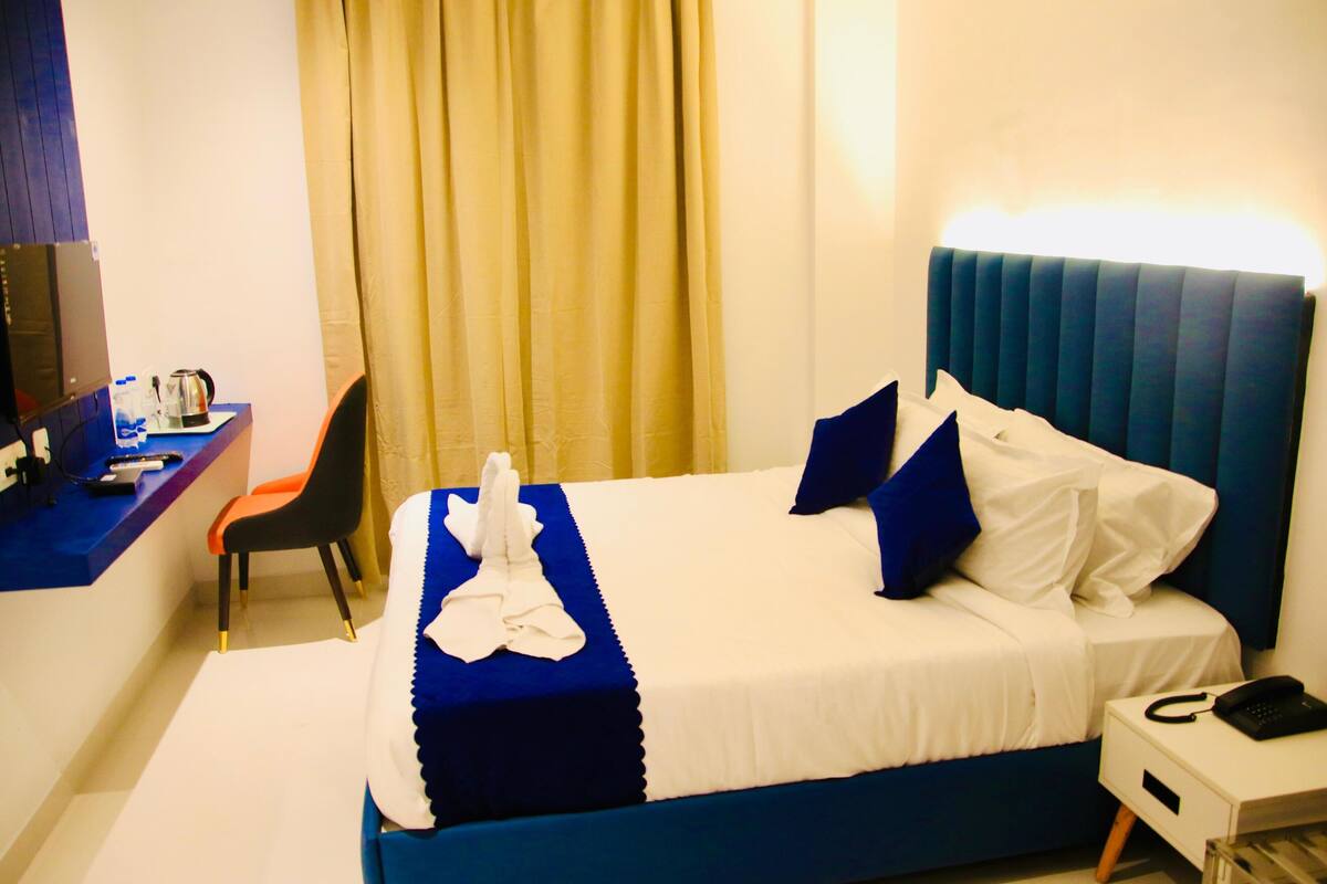 Una habitación de hotel con una cama, un escritorio con una silla, un teléfono y un televisor.