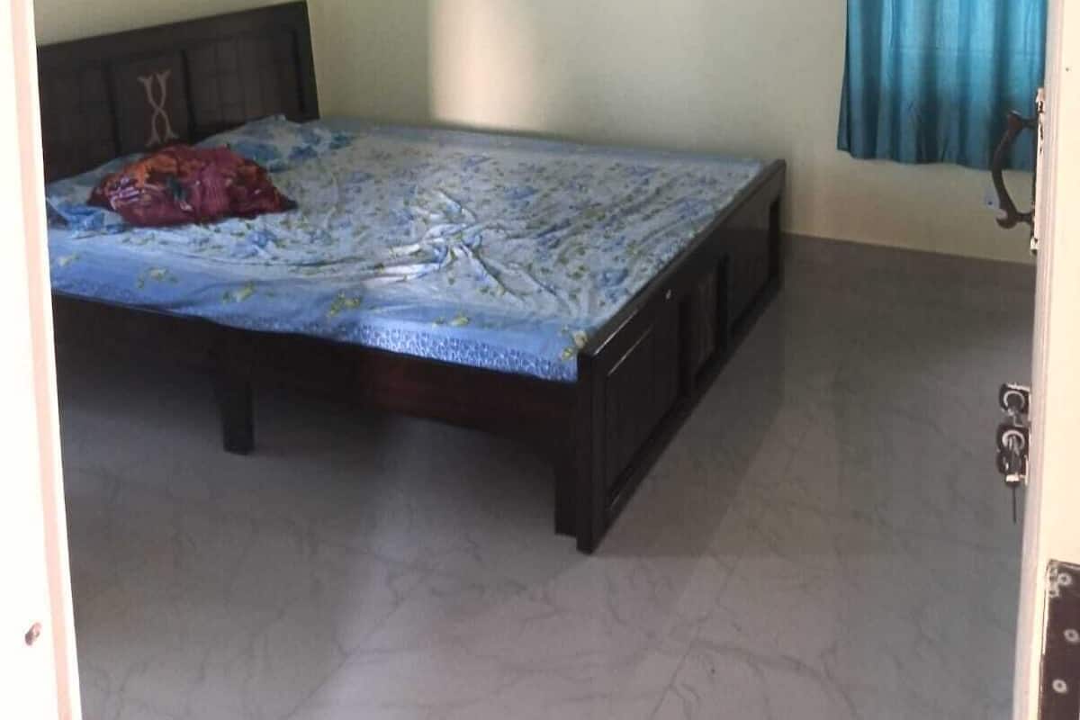 Una camera da letto con un letto, una ventola a soffitto, una finestra con tende e una presa elettrica a muro.