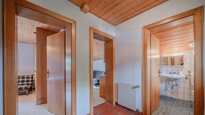 Een gang met houten deuren die leiden naar een slaapkamer en een badkamer.
