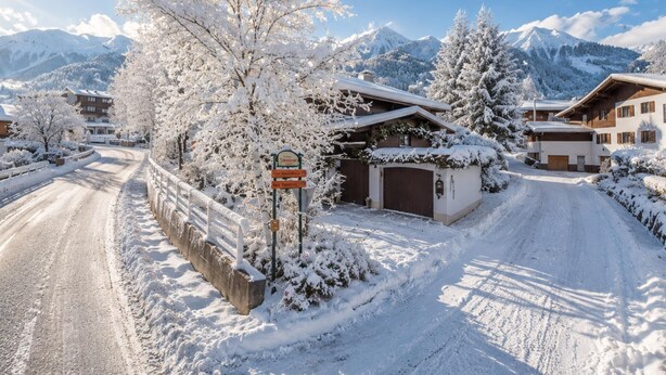 Een besneeuwde bergdorp met een weg naar een gebouw met een garage.