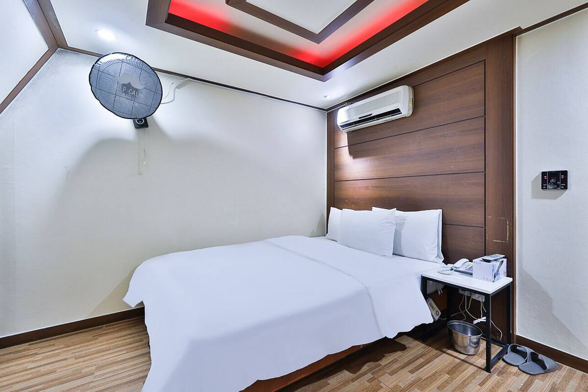 A hotel room with a bed, bedside table, and a ceiling fan.