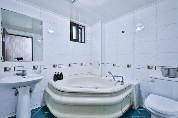 A bathroom with a large bathtub, a sink, and a toilet.