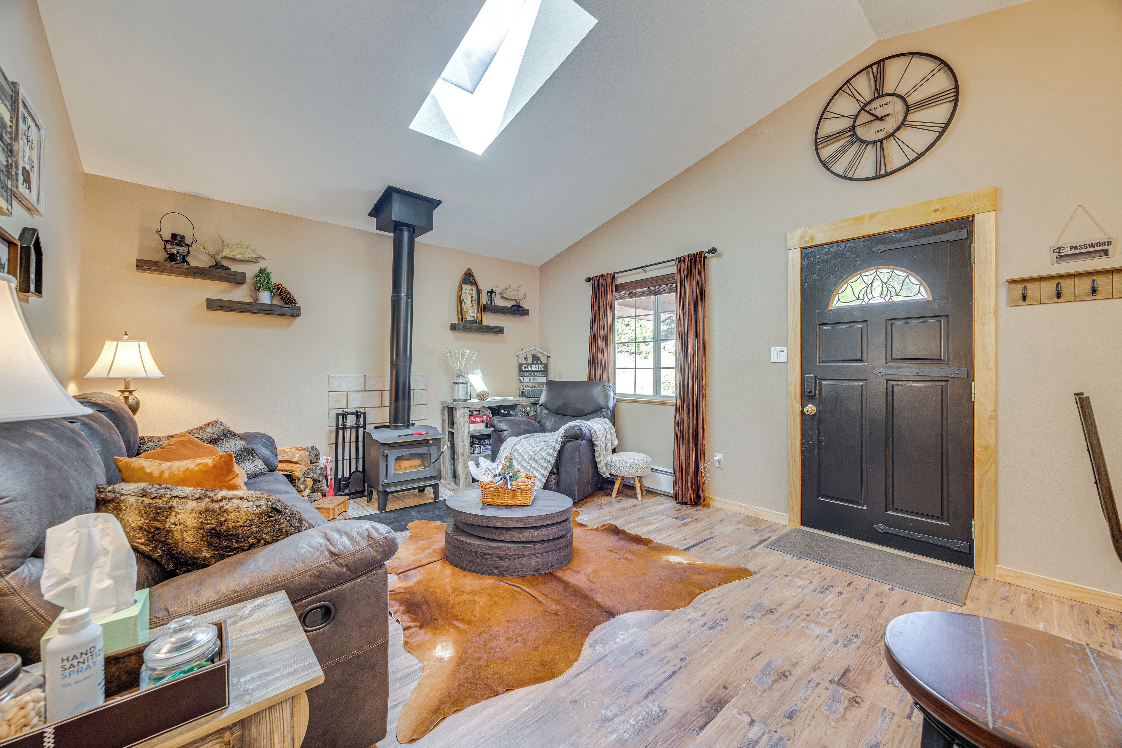 A cozy living room with a leather sofa, a round coffee table, a fireplace, and a wooden door with a glass window.