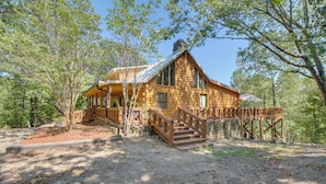 A log cabin with a wooden deck and stairs leading to the entrance. - Hot Springs Cabin w/ Deck + Mountain Views! (Hot Springs)