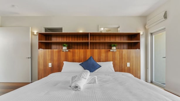 A hotel room with a large bed, wooden headboard, two bedside tables with lamps, and a window with a view. - Mountain Majesty with Poolside: Relaxing Getaway (Tamborine)