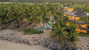 A resort with a pool, palm trees, and a beach area.