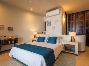 A modern bedroom with a large bed, bedside tables, a wall-mounted air conditioner, and a decorative wall panel. - Mar de Coco Areca 101 (Playa Blanca)