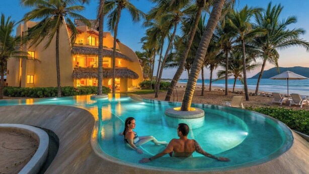 A resort pool with a curved design, palm trees, and a building with a thatched roof.