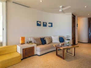 A modern living room with a sofa, a yellow armchair, a wooden coffee table, and artwork on the wall.