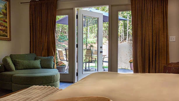 Un dormitorio con cama, sofá verde y vista a un patio exterior.