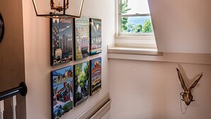 Una escalera con vistas al exterior a través de una ventana, decorada con carteles de viajes y una cabeza de animal montada.