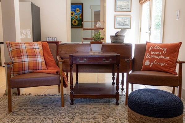 Un salon chaleureux avec deux fauteuils en cuir marron, une table basse en bois et un pouf bleu.