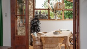 A dining area with wicker furniture, a table with a beige tablecloth, and a hanging light fixture. - Beautiful Cottage nr Mendip Hills, Private Parking (Chilcompton)