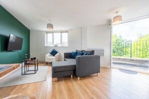 Relax in this stylish living room with a large sofa, armchair, and flat-screen TV.