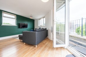 Relax in this stylish living room with a sofa, flat-screen TV, and sliding glass door leading to a balcony.