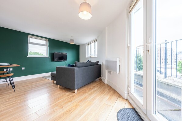Relax in this stylish living space with a large sofa, flat-screen TV, and dining area, plus a balcony with a view.