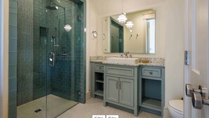 Ein Badezimmer mit einer Duschkabine, einem Waschbecken mit Spiegel darüber und einer Toilette.