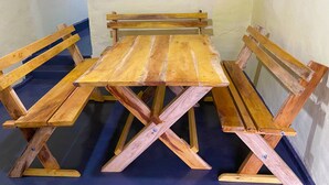 Una mesa de madera con bancos en una habitación con piso azul y una ventana con rejas.