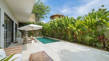 Een buitenzwembad, parasols bij het zwembad en ligstoelen