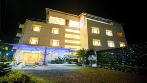 A multi-story hotel with a well-lit entrance and a covered outdoor area.